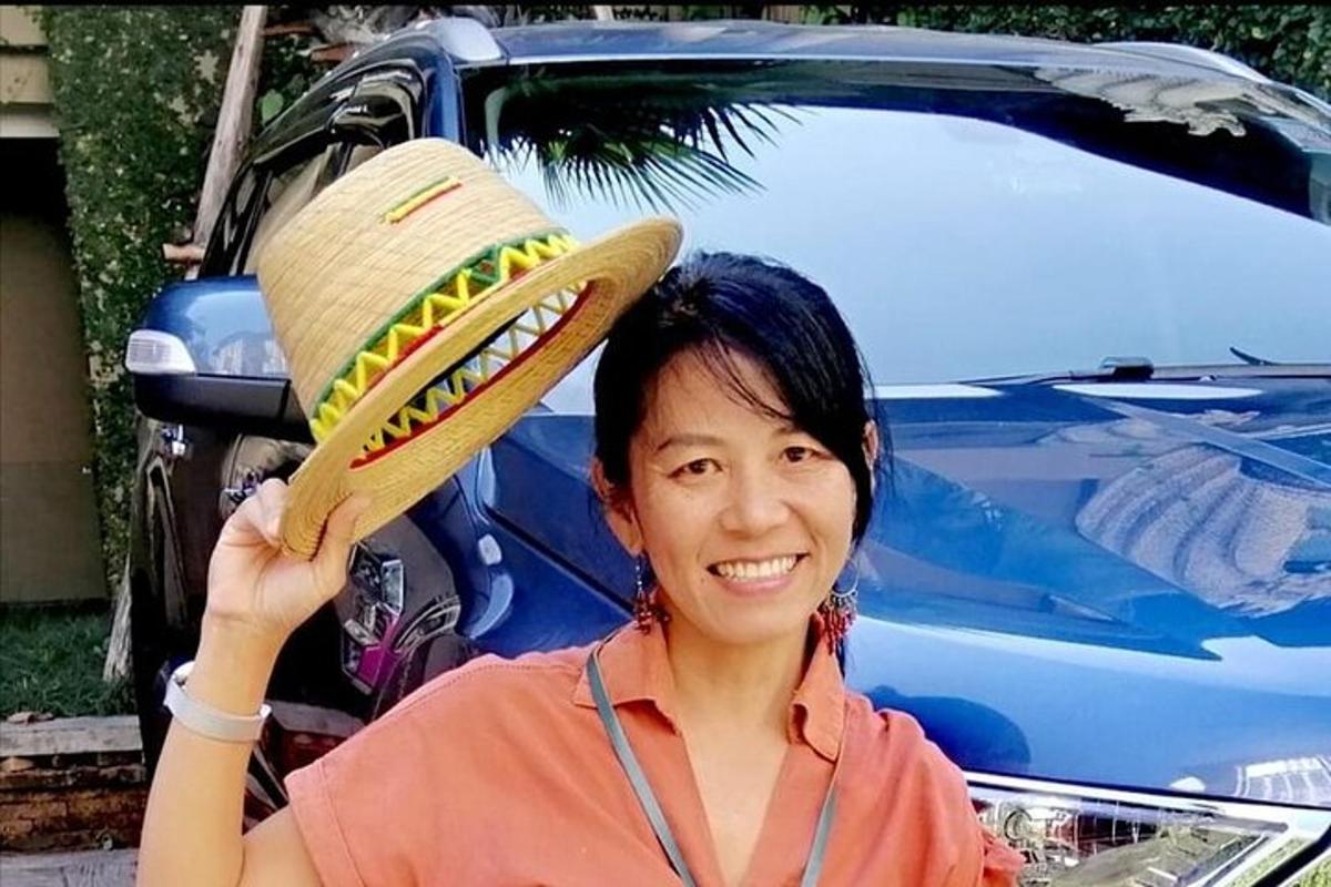 a woman is holding up a straw hat