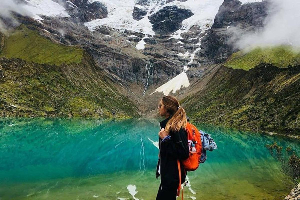 en kvinne som står i vannet nær en fjellsjø