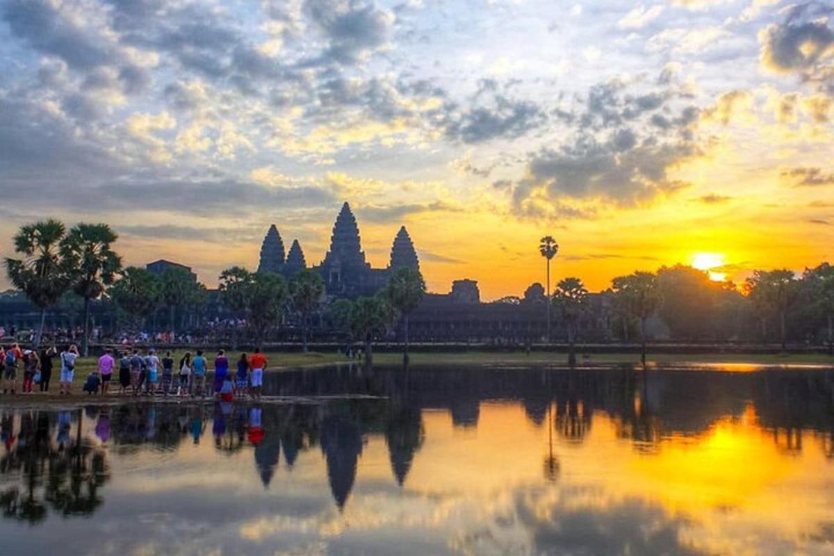 sekumpulan orang berdiri di sekeliling tasik di hadapan matahari terbenam