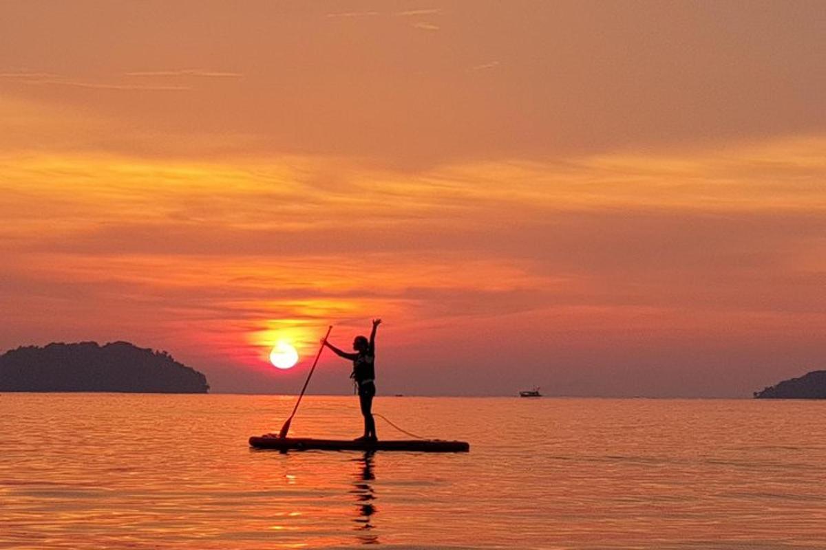 una persona su una tavola da paddle nell'oceano al tramonto