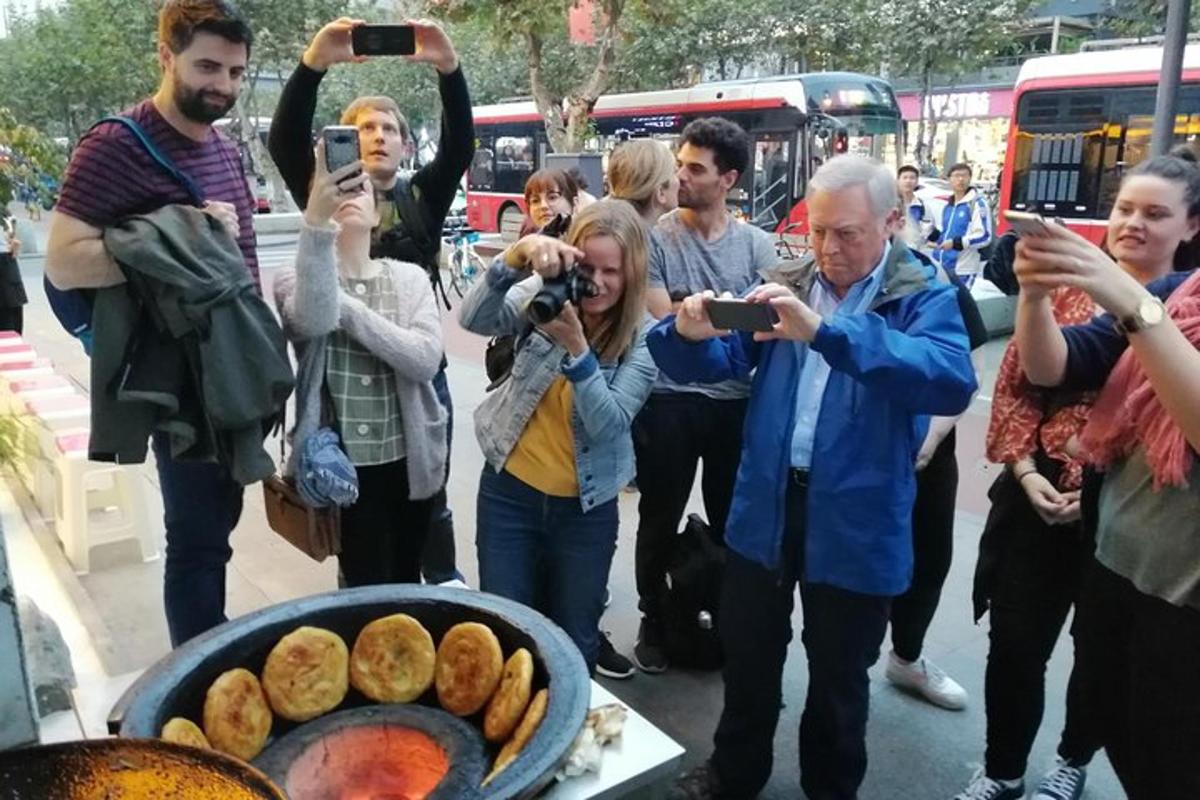 a group of people taking pictures of a grill with food