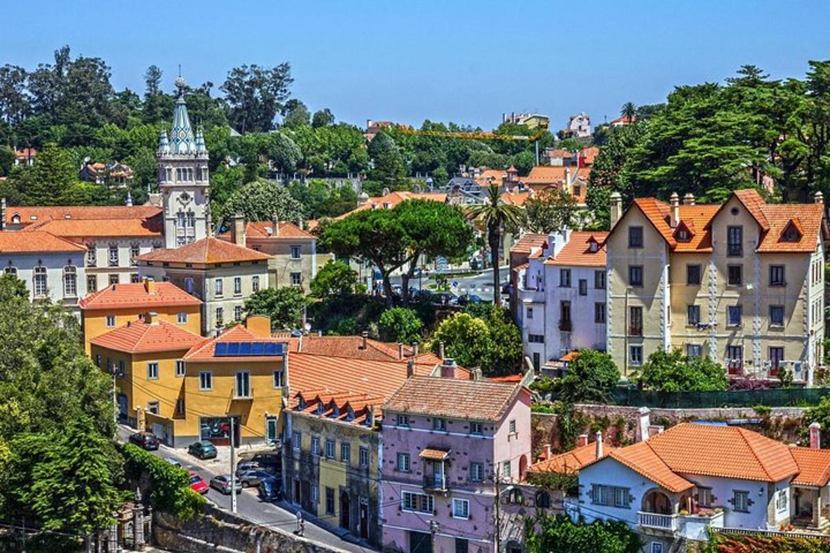 a city with houses and a clock tower on a hill