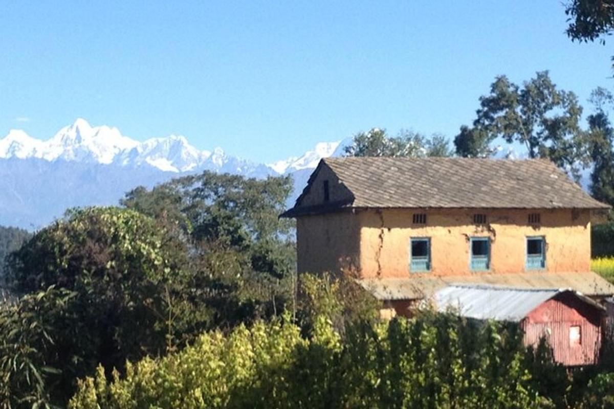 an old house on a hill with mountains in the background