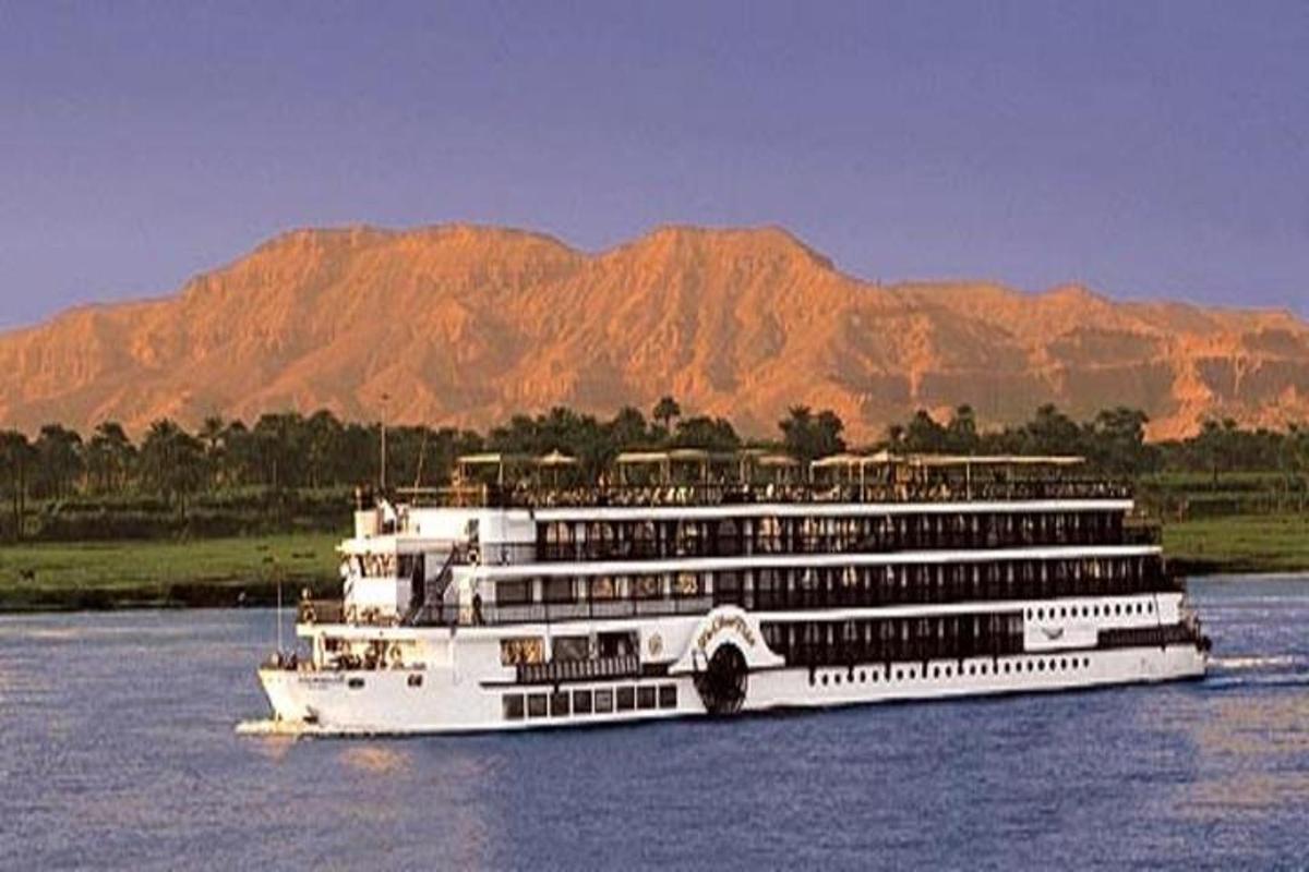 Un crucero en el agua con montañas al fondo.