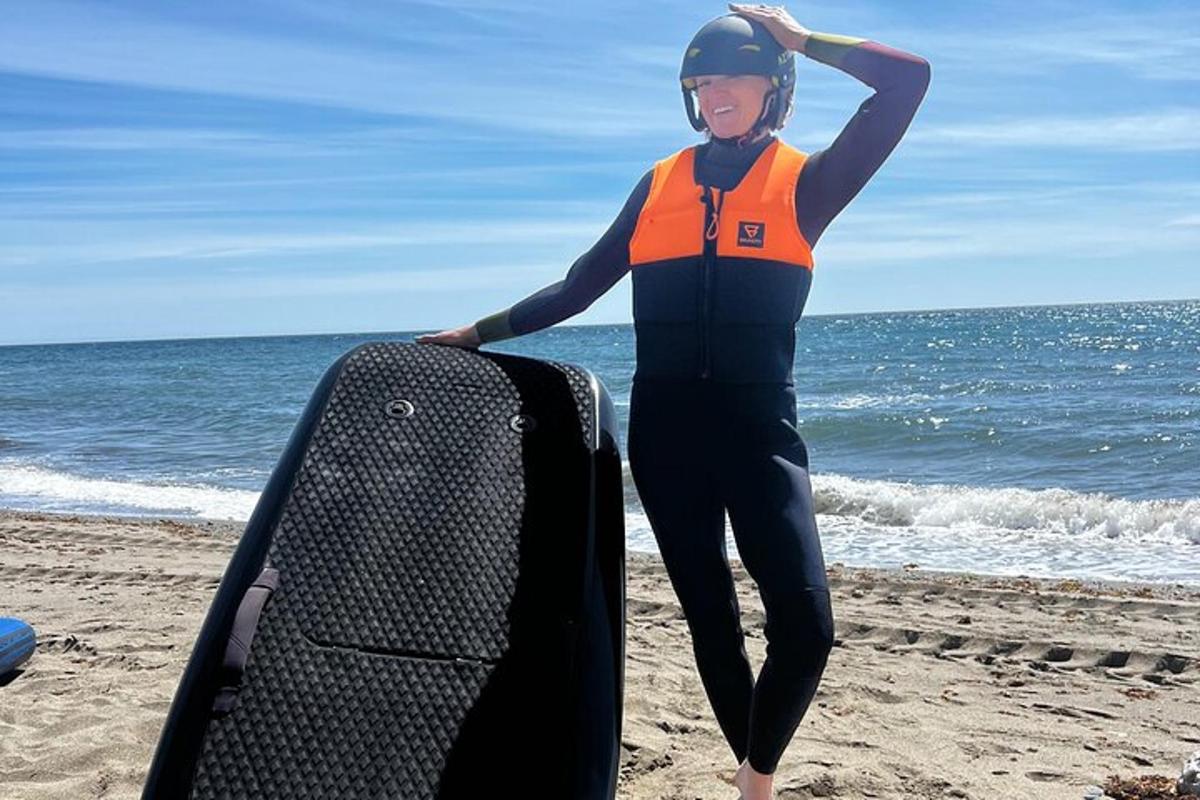 žena stojící na pláži se surfovacím prknem