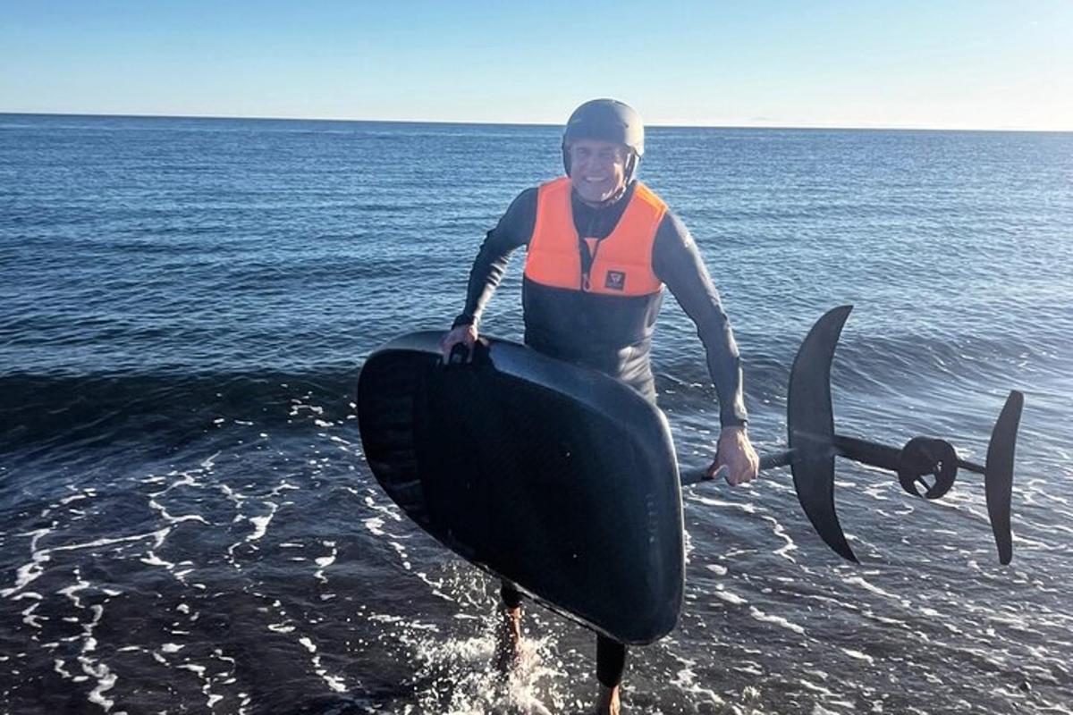 un uomo in piedi nell'acqua che tiene in mano una tavola da surf