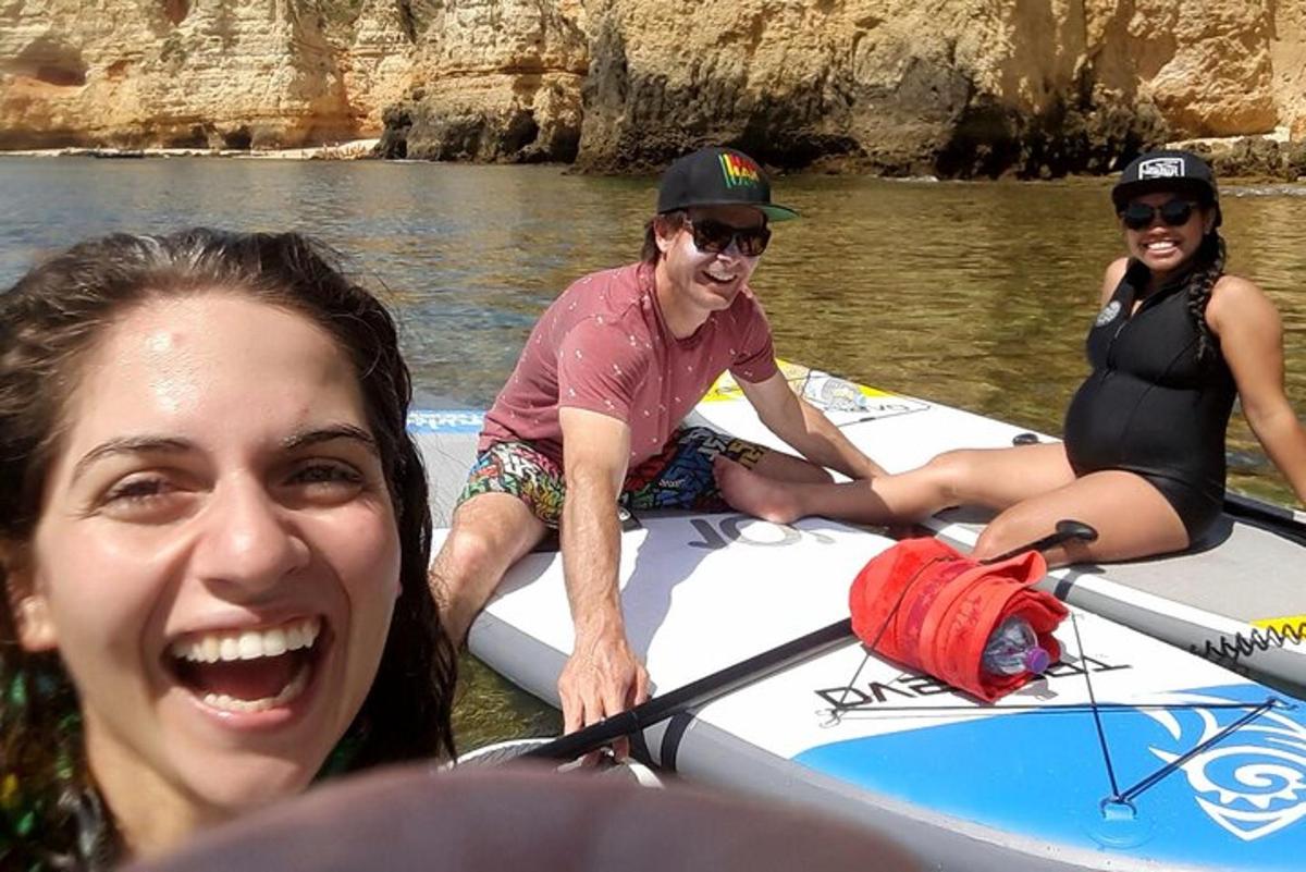tre persone su una tavola da paddle in acqua