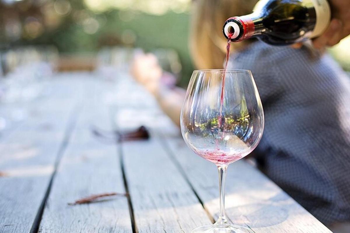 inimene valab veini puidust laual olevasse veiniklaasi