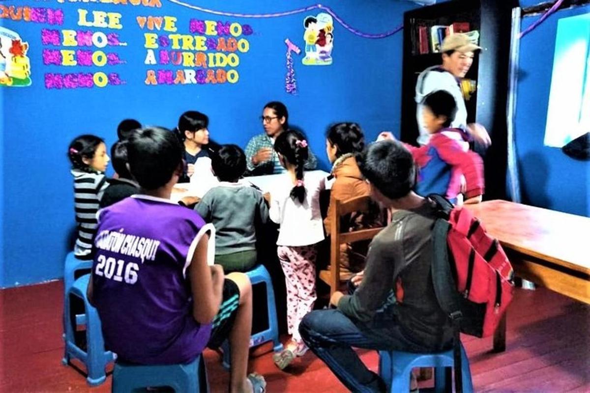 một nhóm trẻ em ngồi quanh một cái bàn trong phòng