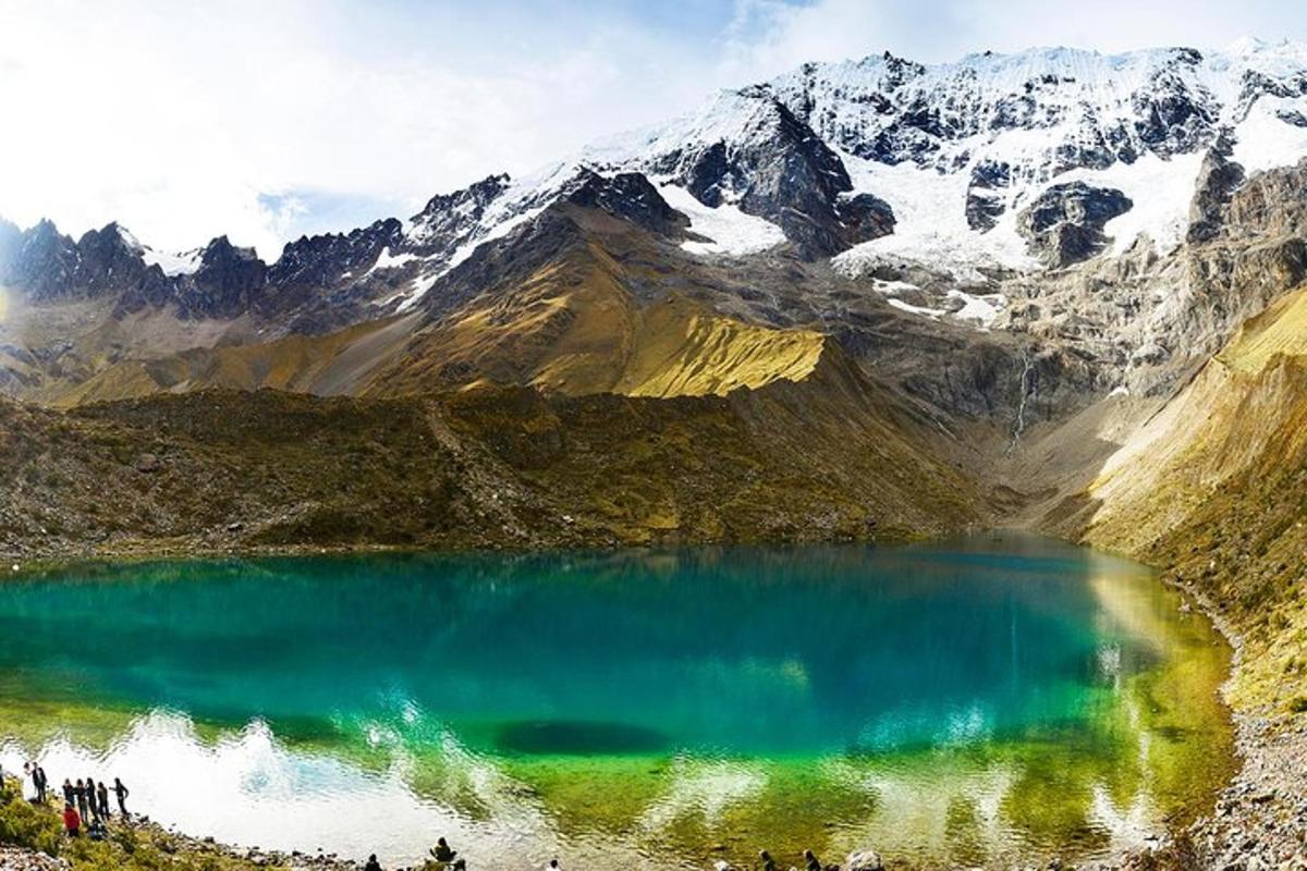 a group of people standing around a mountain lake