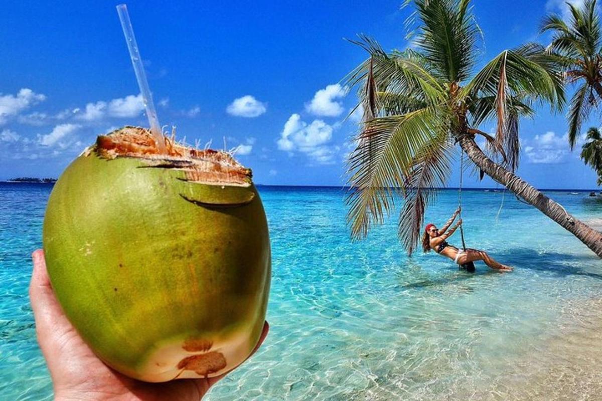 una persona sosteniendo un coco frente a una playa