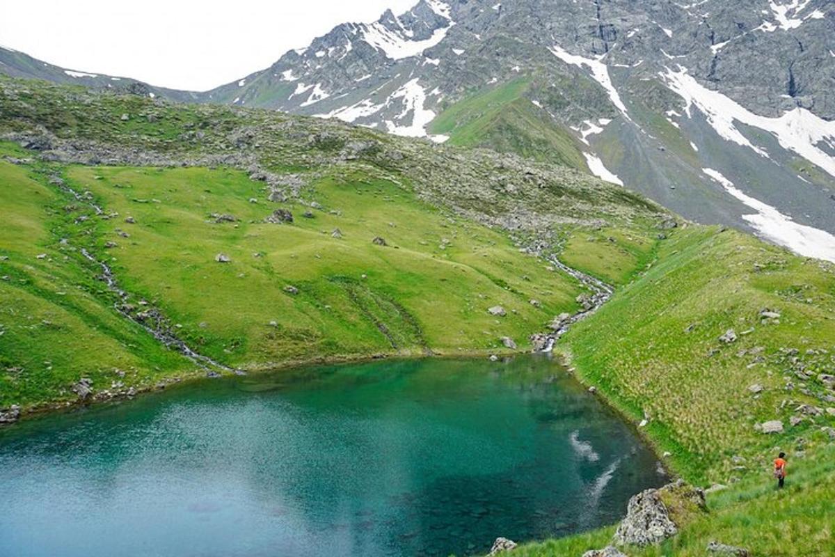 seseorang yang berdiri di sebelah tasik di atas gunung