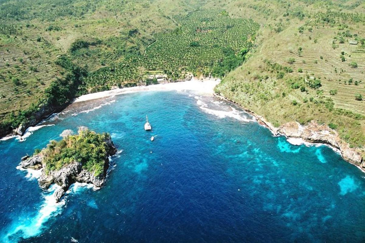 suda bir tekne bulunan bir plajın havadan görünümü