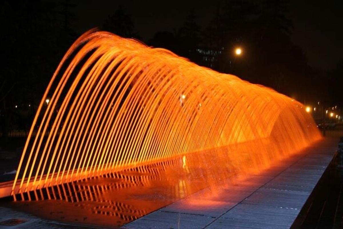 a large water fountain is lit up at night