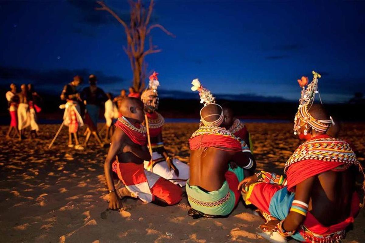 en gruppe mænd sidder på stranden om natten