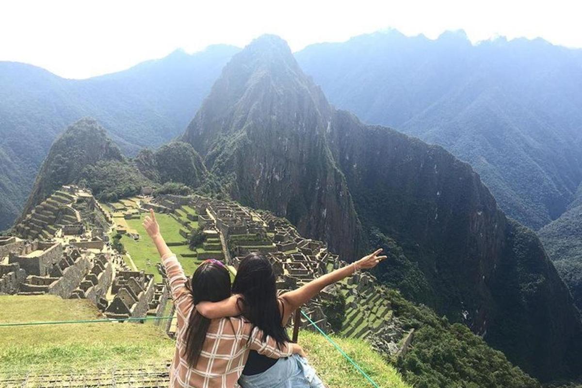 two people standing on top of a mountain with their arms up