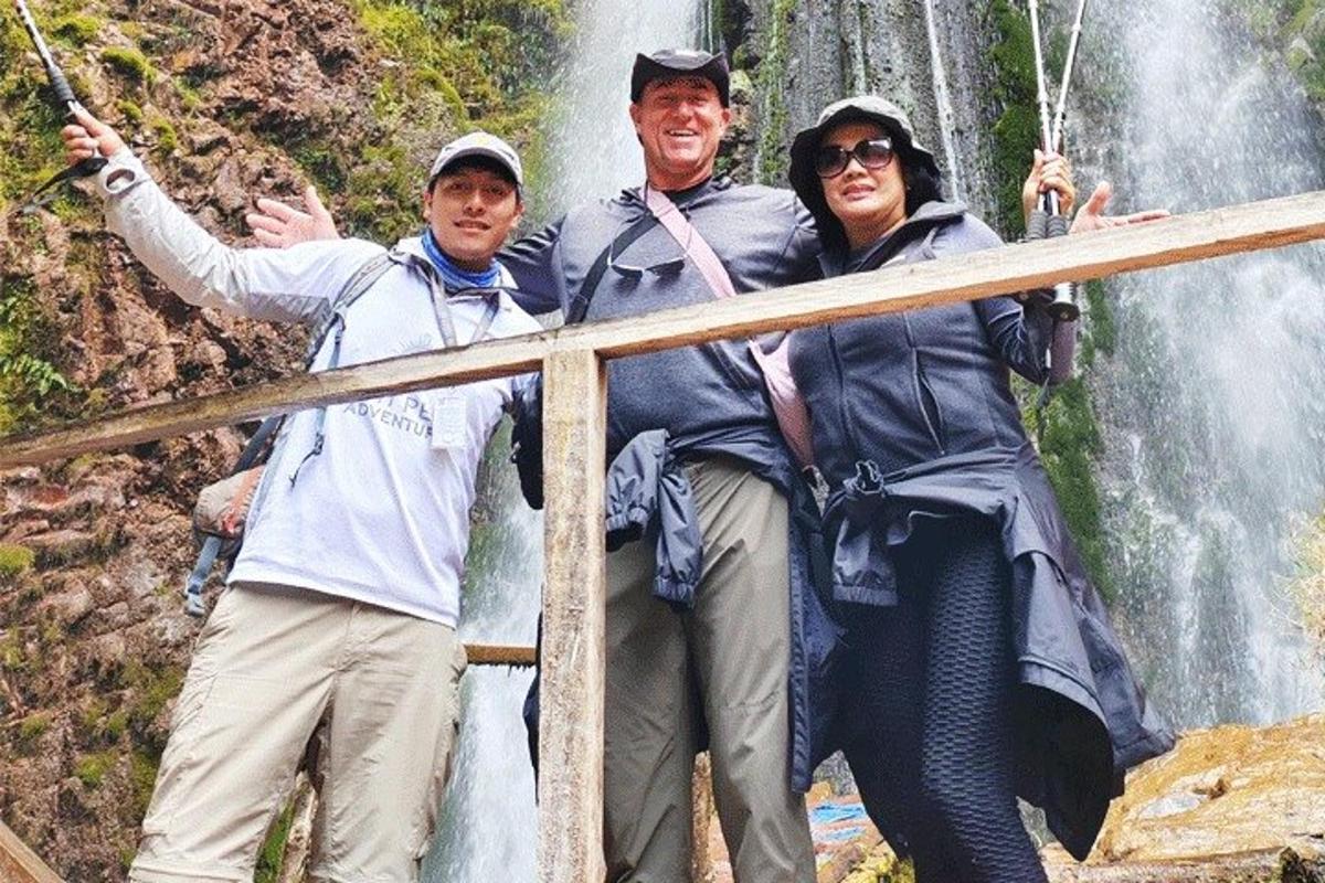 sekumpulan tiga orang berdiri di hadapan air terjun