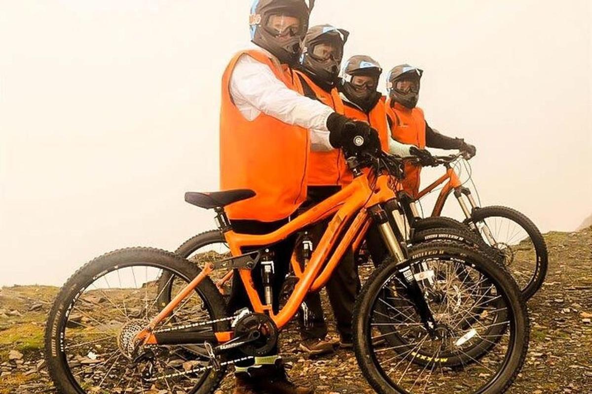 skupina mužov v oranžových bundách stojacich vedľa svojich bicyklov