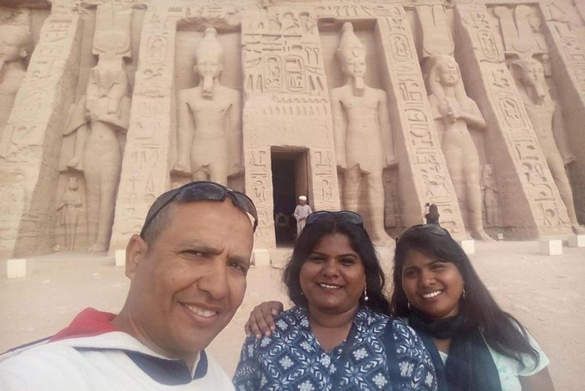 um homem e duas mulheres em pé em frente ao arco