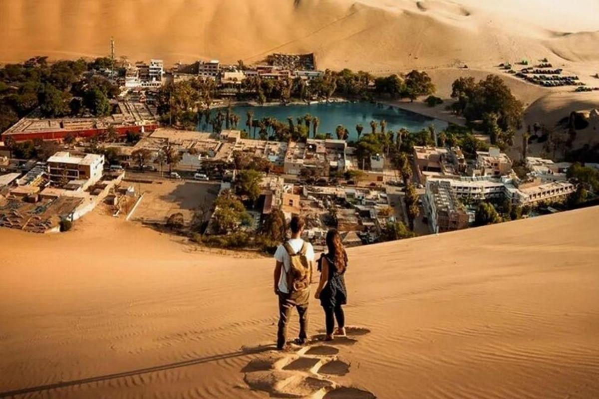 a man and woman standing on top of a sand hill