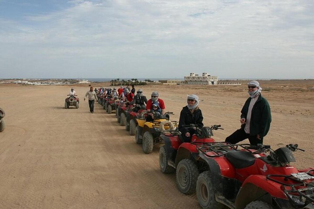 un gruppo di persone in piedi attorno ai quad nel deserto