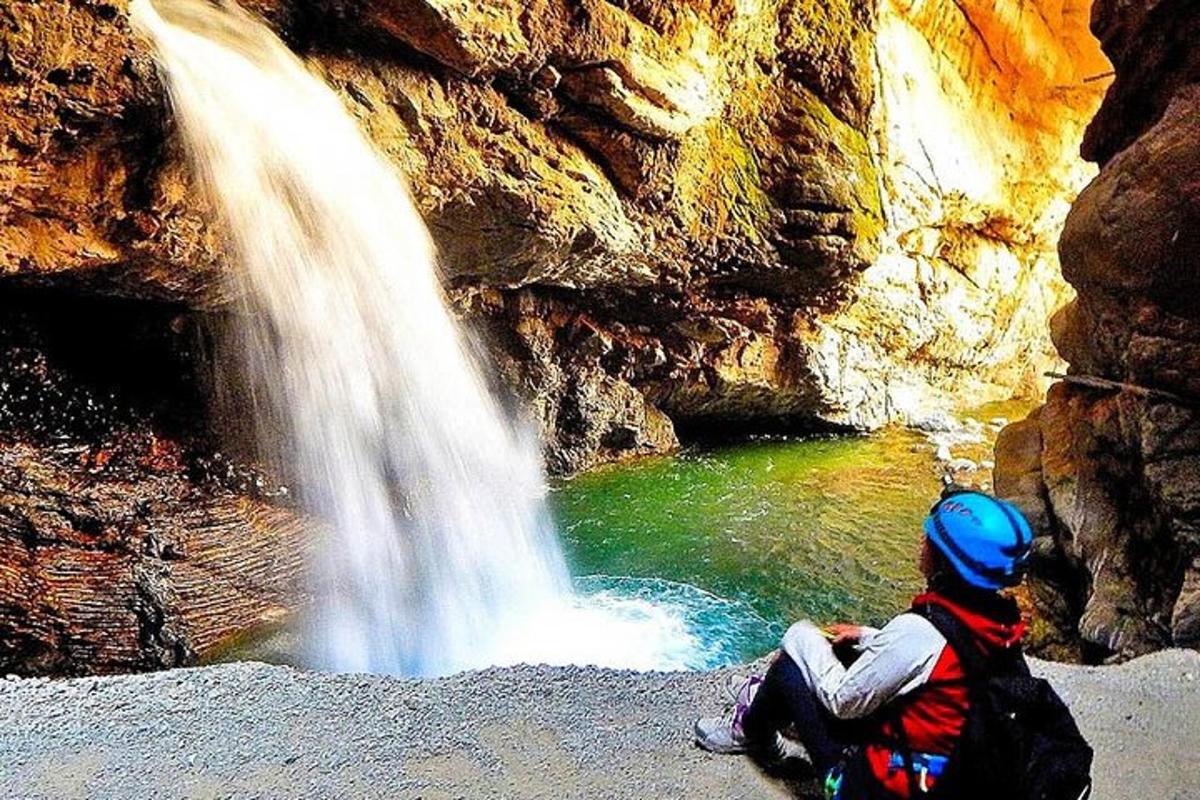 eine Person, die neben einem Wasserfall auf dem Boden sitzt