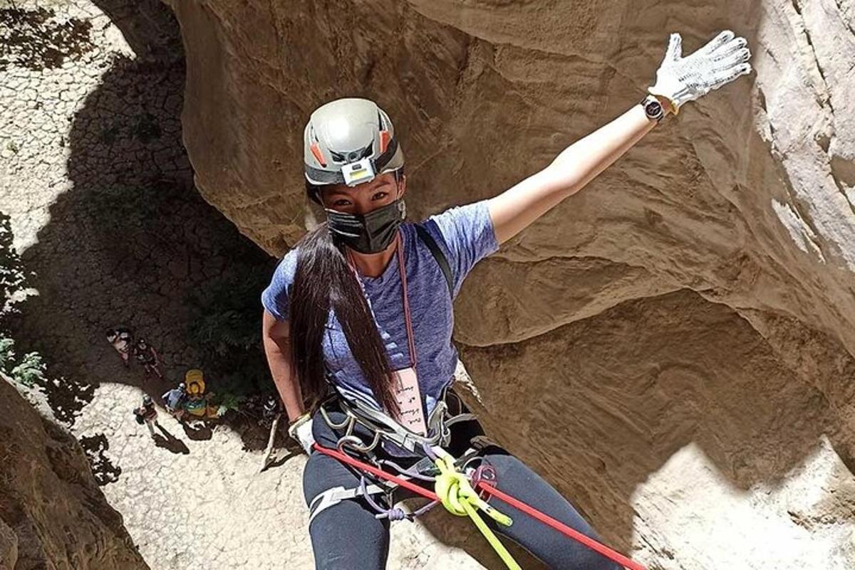 eine Frau seilt sich von einer Felswand ab