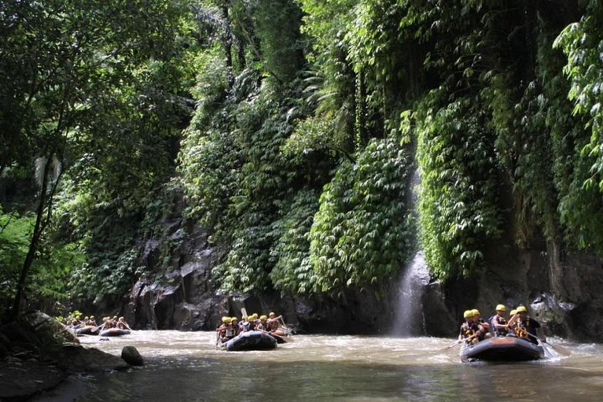 a group of people riding on elephants in the water near a waterfall