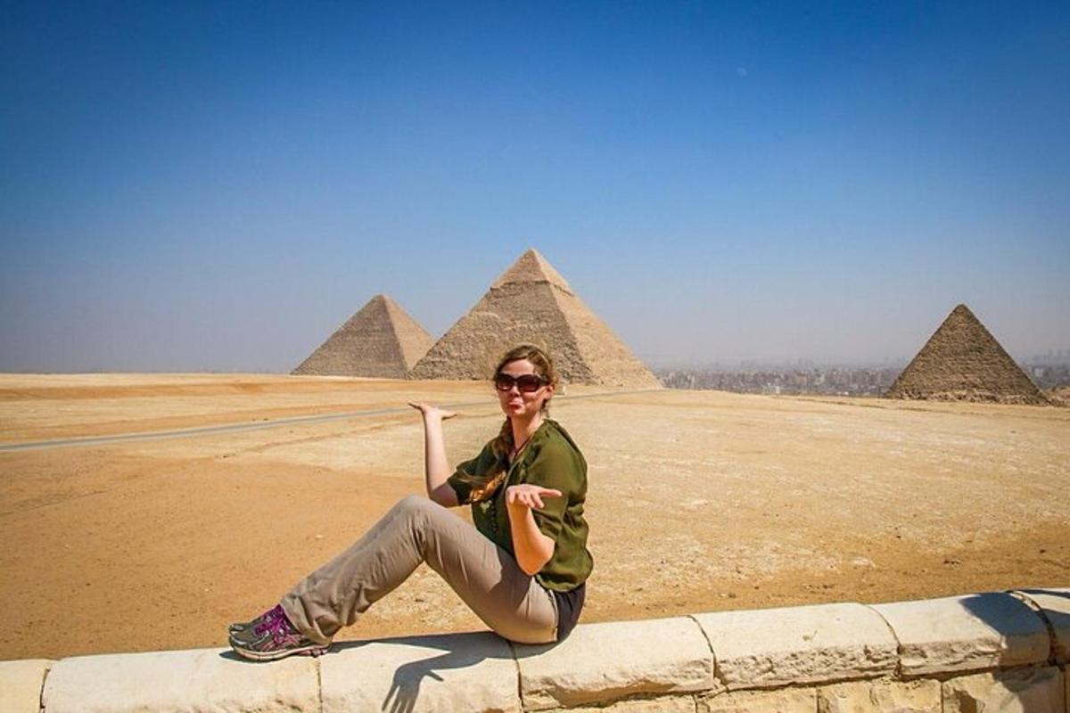 žena sedící na zdi před pyramidami