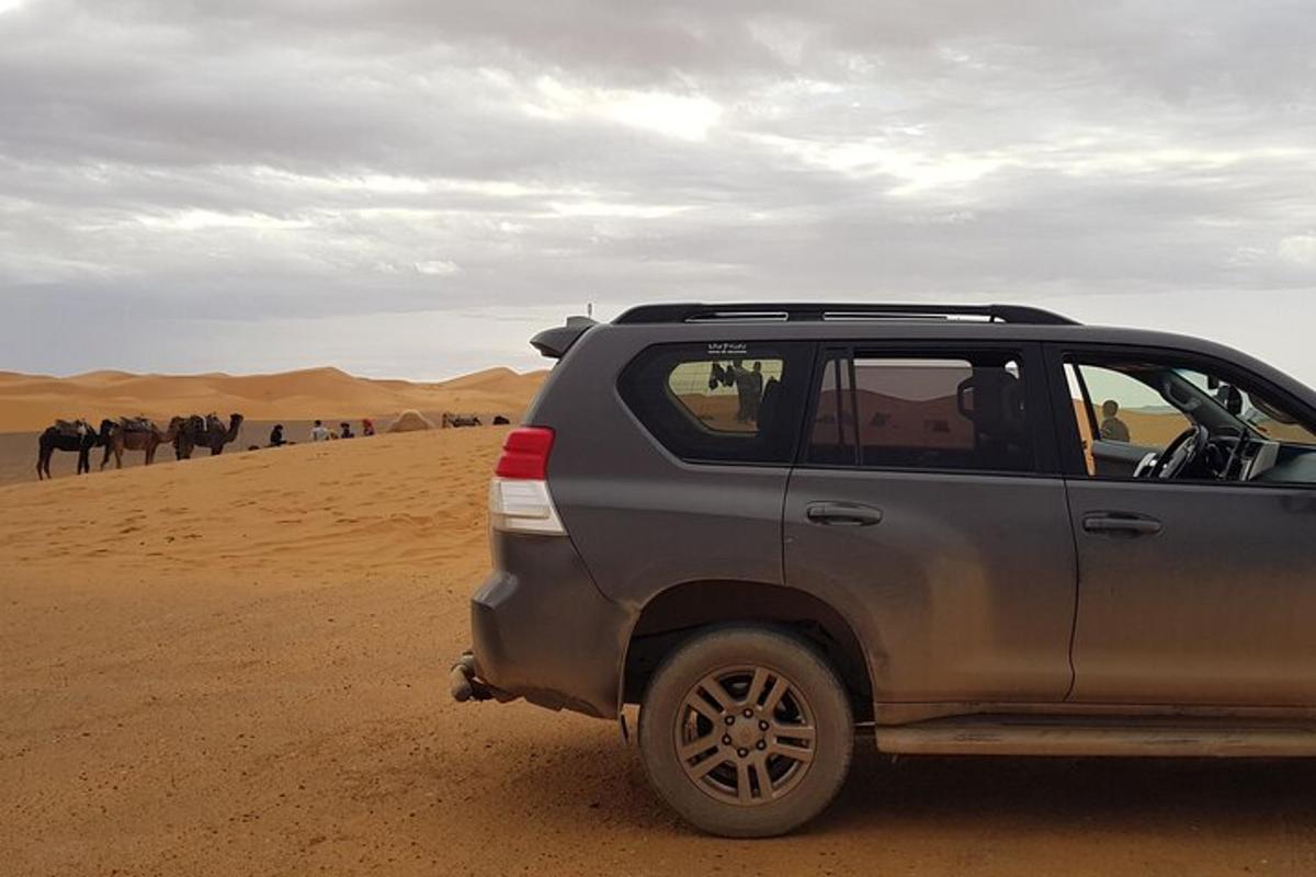 um carro estacionado no deserto com um grupo de pessoas
