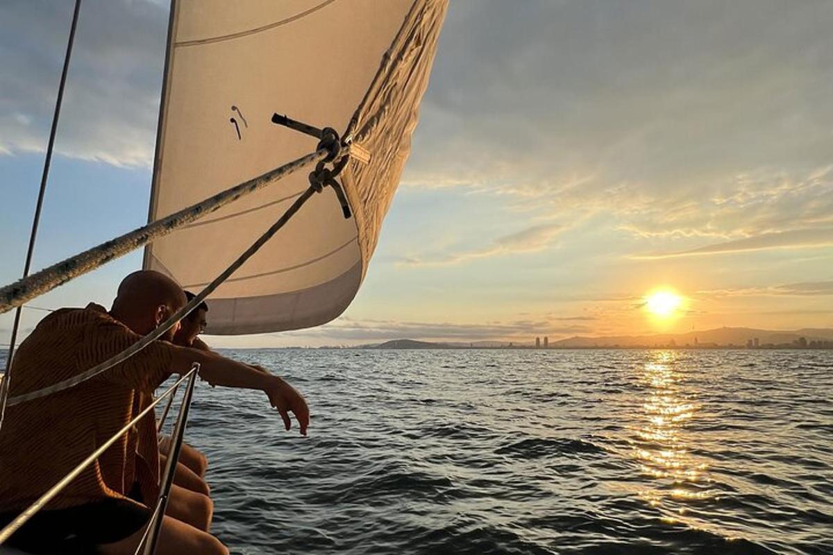 seorang pria di atas perahu layar di lautan saat matahari terbenam