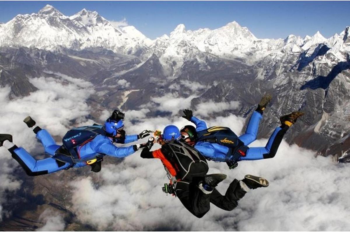 a group of people flying in the air over a mountain