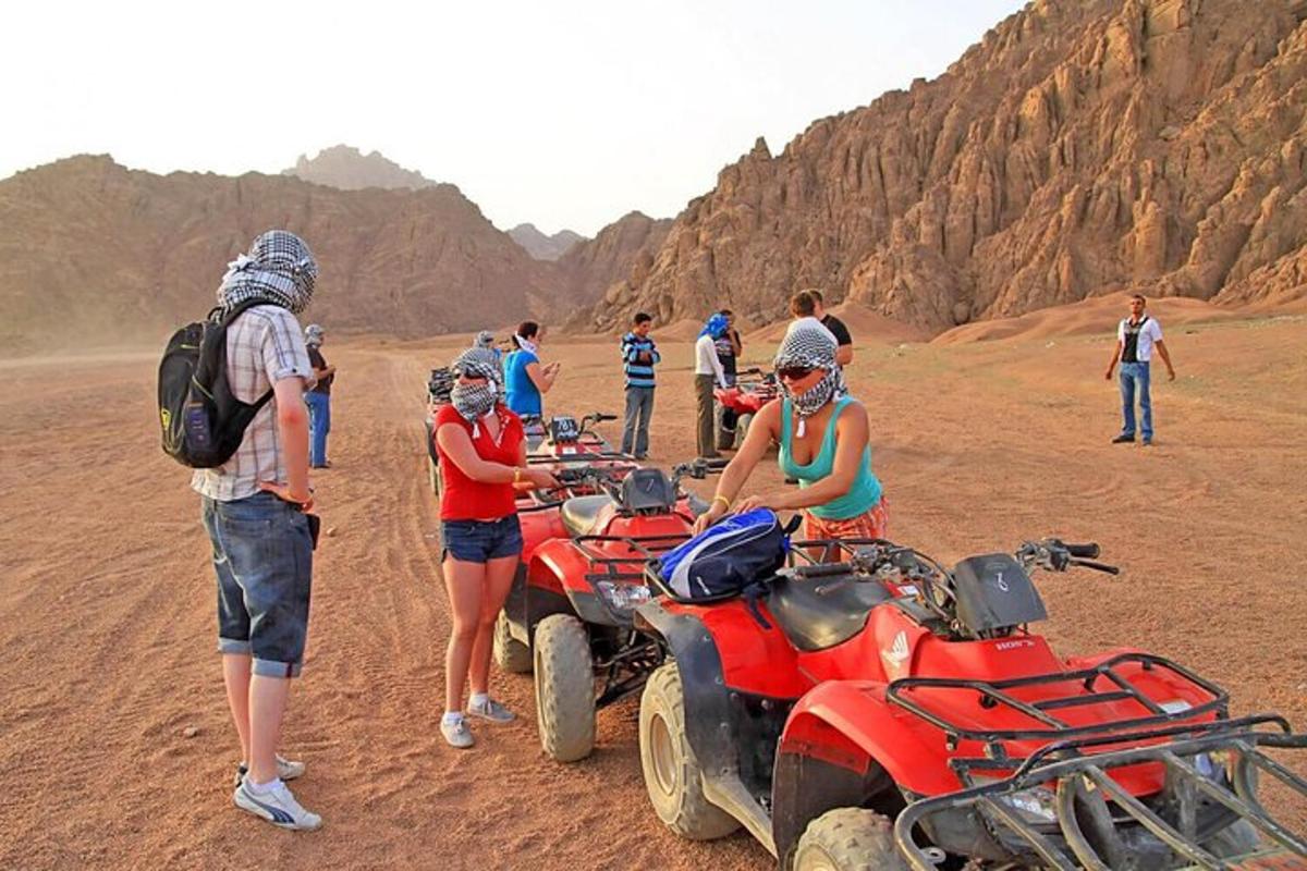 um grupo de pessoas em pé ao redor de quadriciclos no deserto