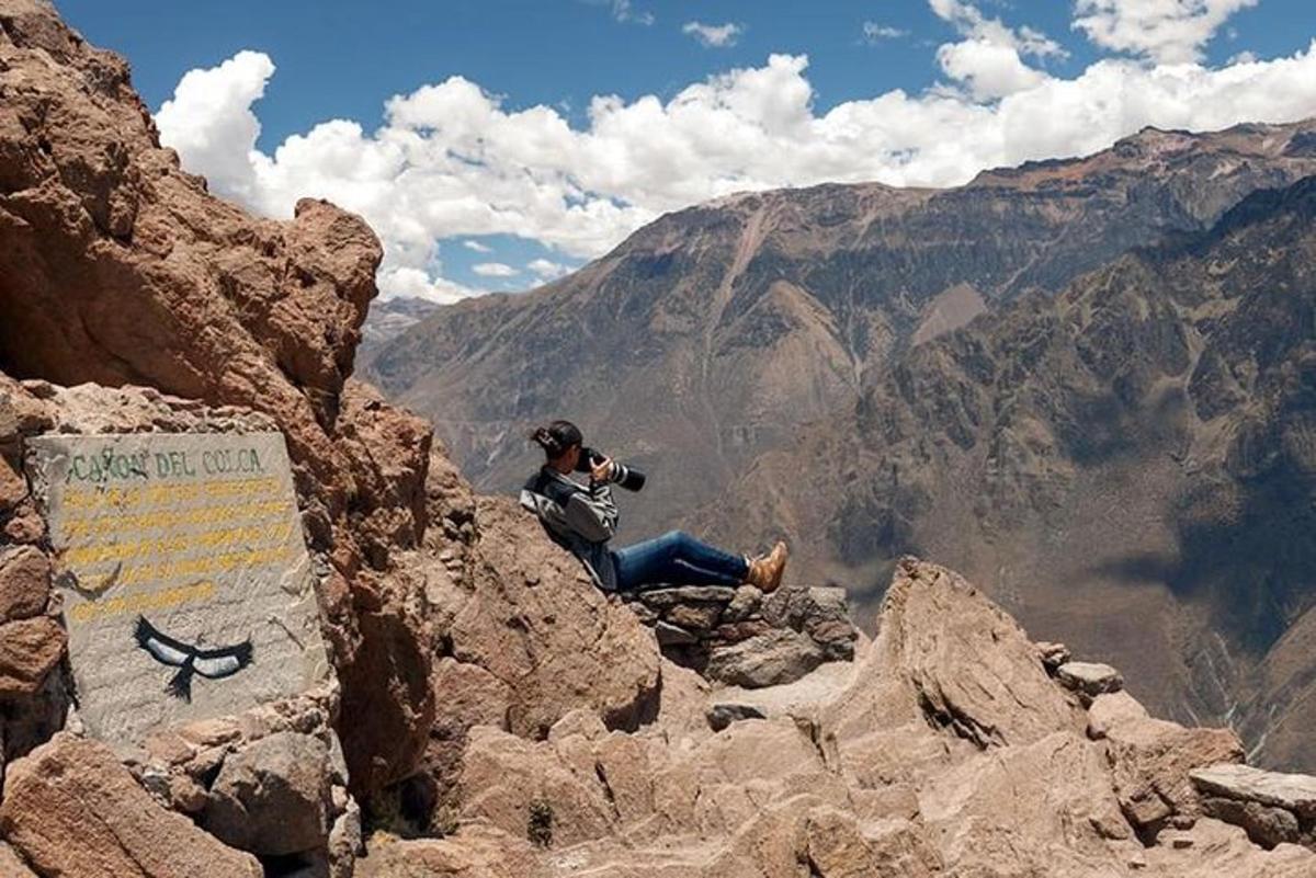 a man sitting on the edge of a mountain taking a picture