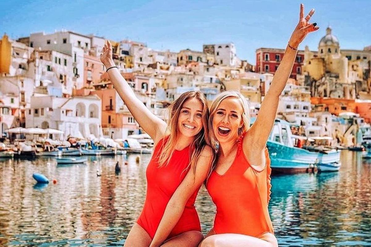 two women in red bathing suits sitting next to the water