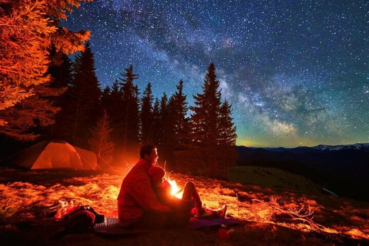 un uomo e una donna seduti attorno a un fuoco da campo di notte