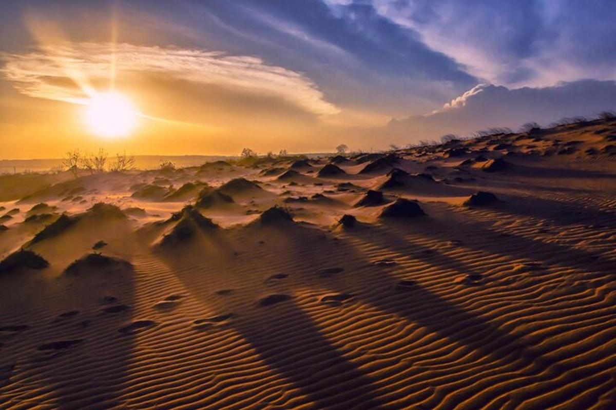a desert with the sun setting in the horizon