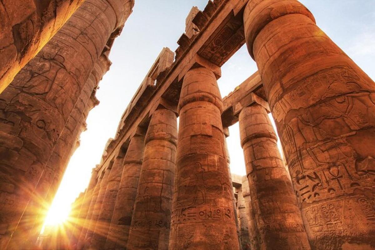 ancient columns of a building with the sun behind it
