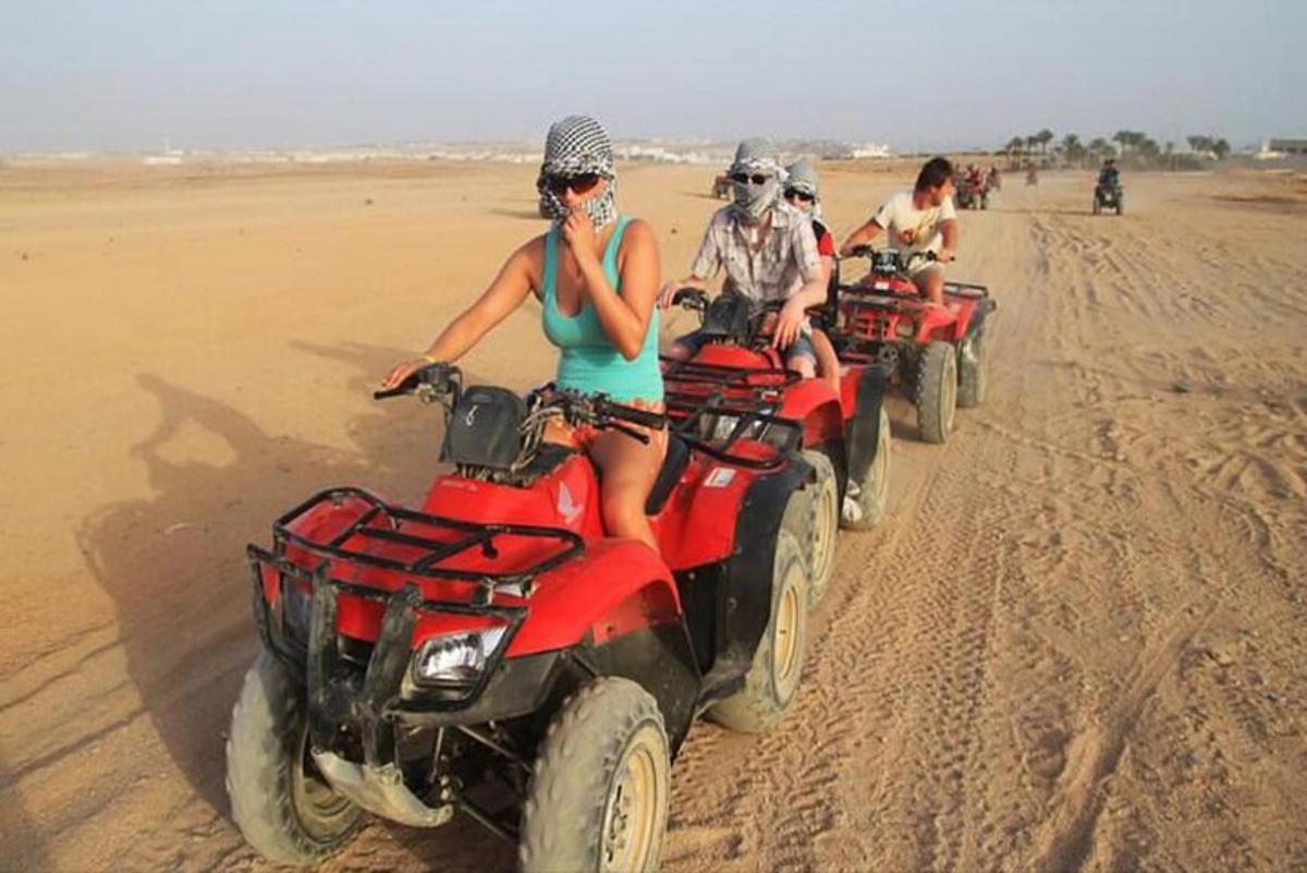 un grup de persones conduint quads al desert