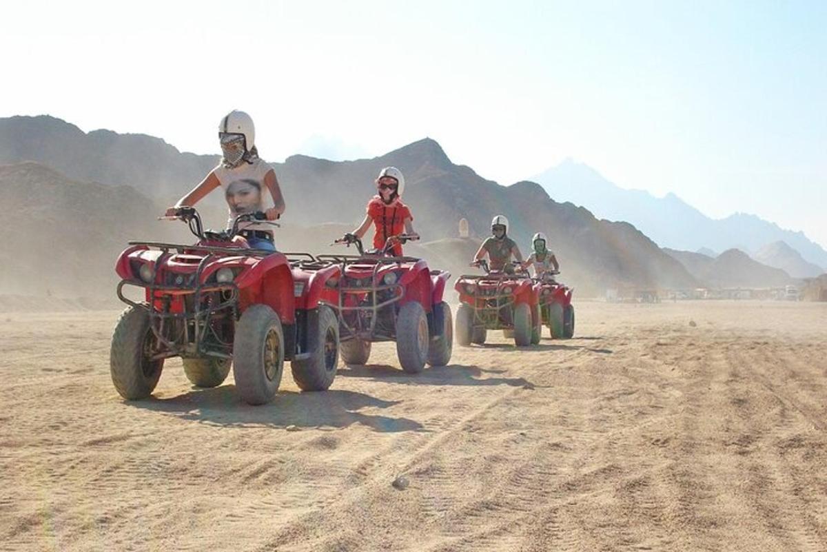 un grup de persones conduint quads al desert