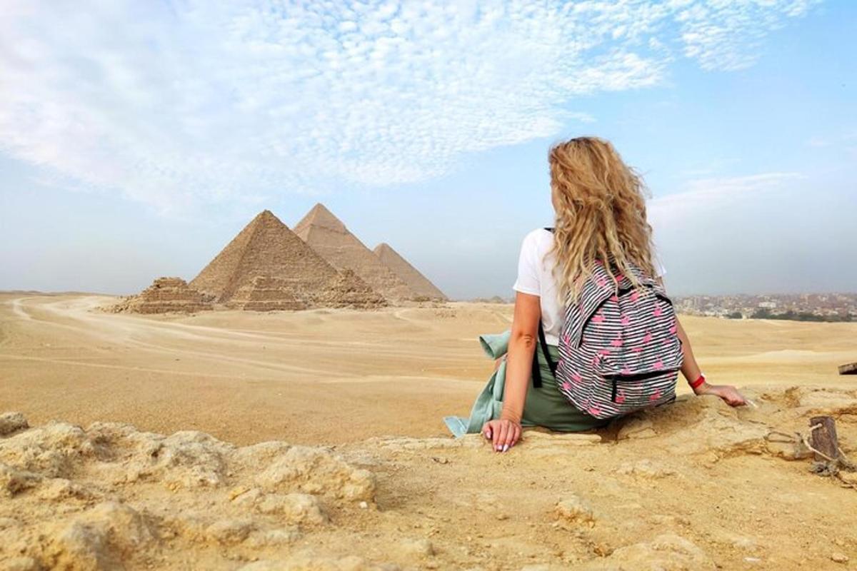 žena sedící na skále před pyramidami
