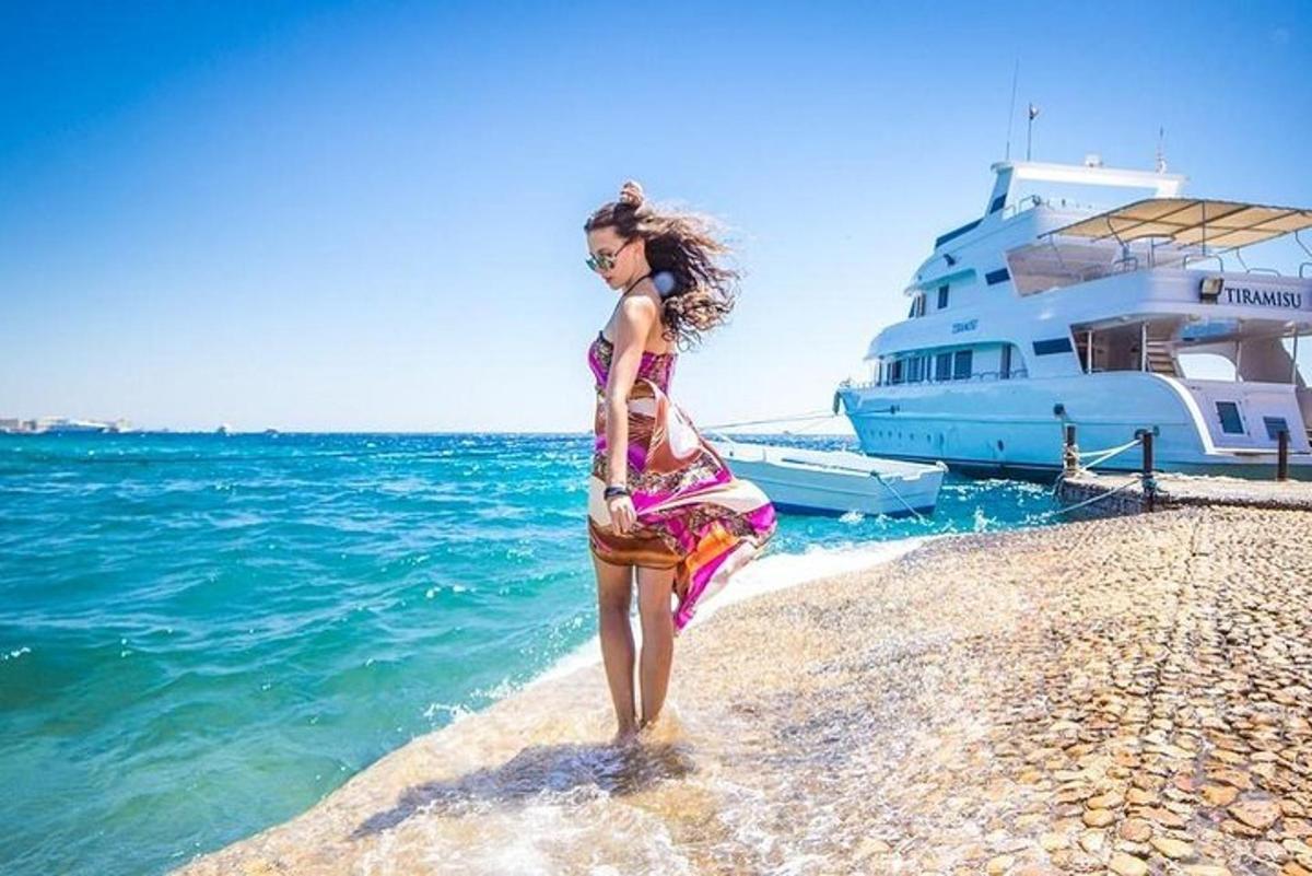 una donna in piedi su una spiaggia accanto a uno yacht