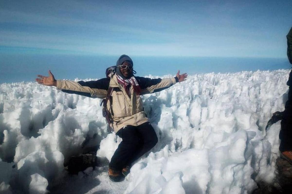 seseorang yang berdiri di atas gunung yang dilitupi salji