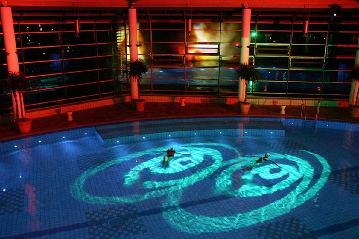 duas pessoas nadando em uma piscina à noite