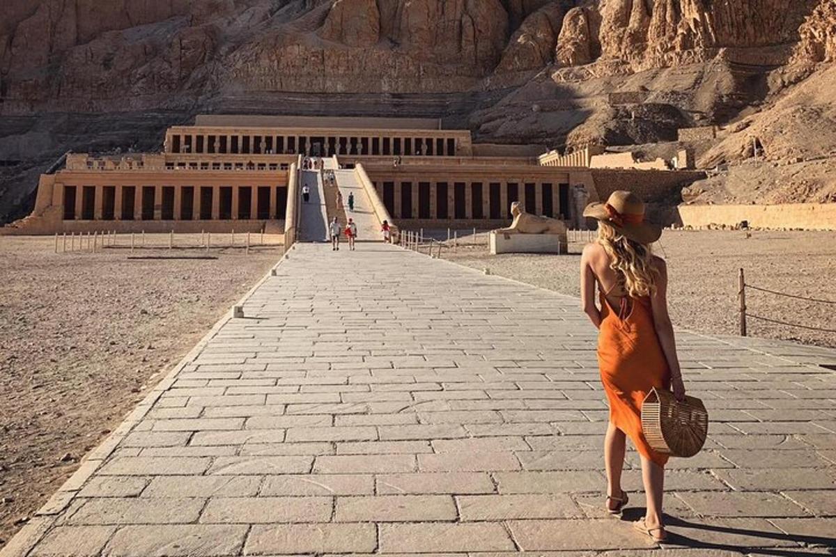 Una mujer con un vestido naranja parada frente a un edificio.