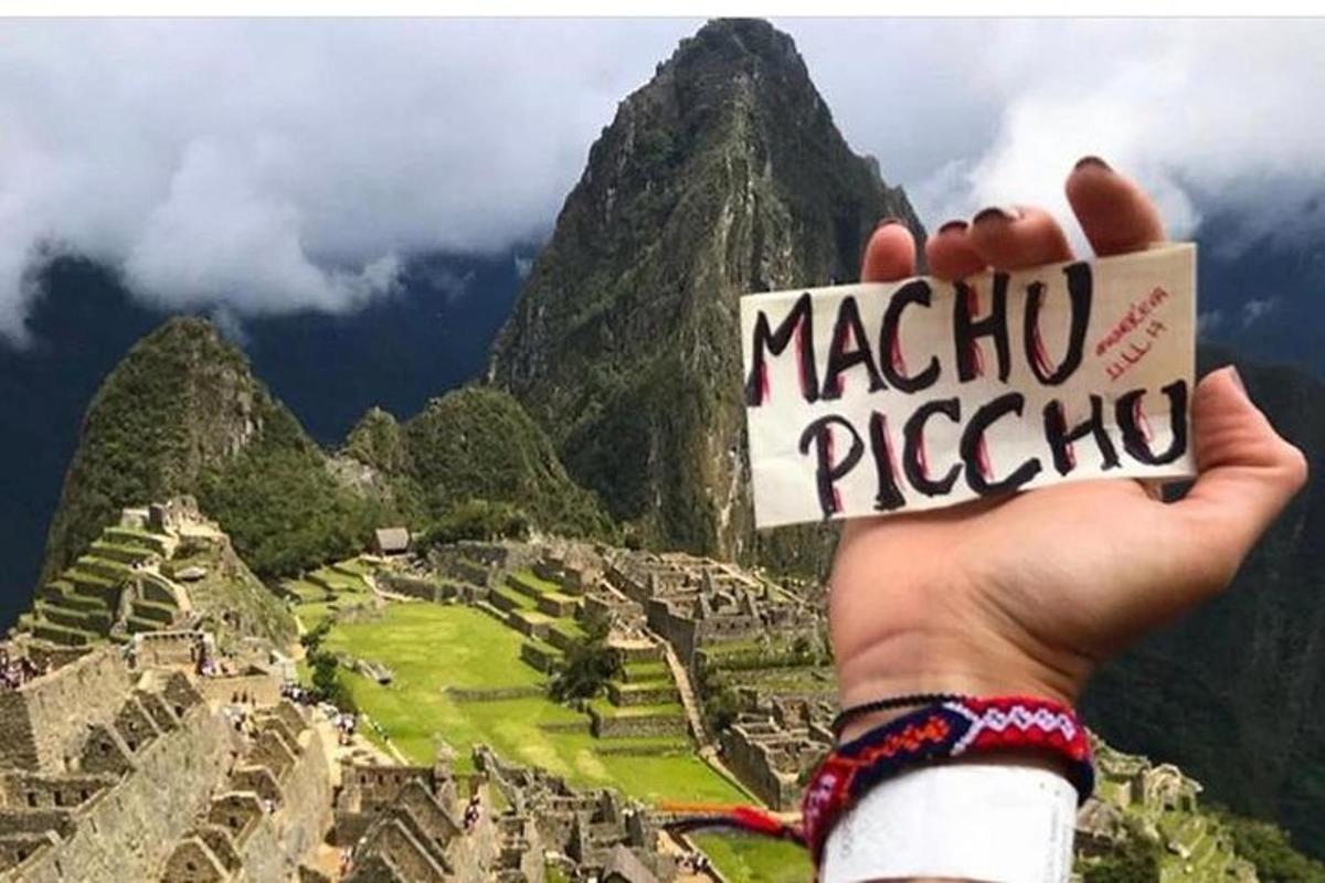 käsi, mis hoiab üleval silti kirjaga Machu Picchu