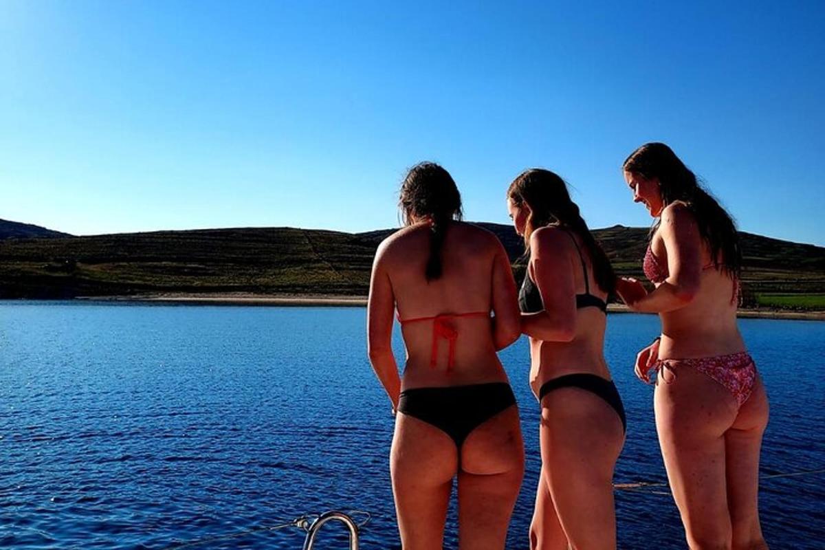 tre donne in bikini in piedi sulla riva di un lago