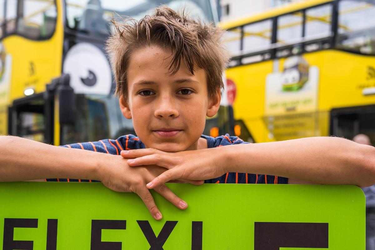 Un niño pequeño sosteniendo un cartel verde con sus manos.