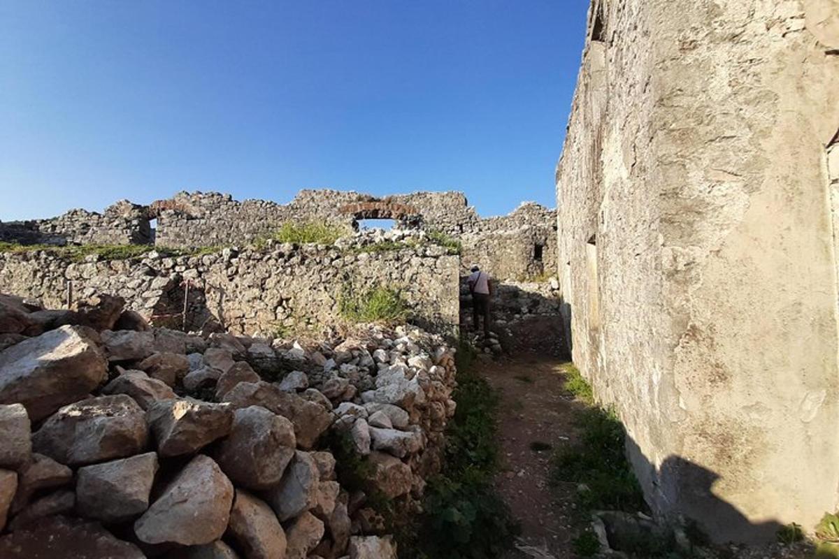 osoba stojící vedle kamenné zdi