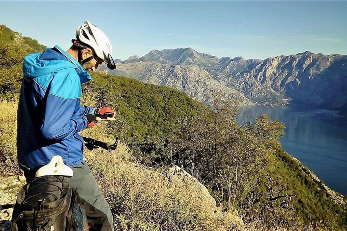 muž stojící na vrcholu hory s výhledem na jezero